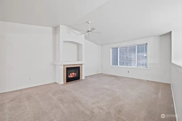 Living room with gas fireplace and vaulted ceiling.