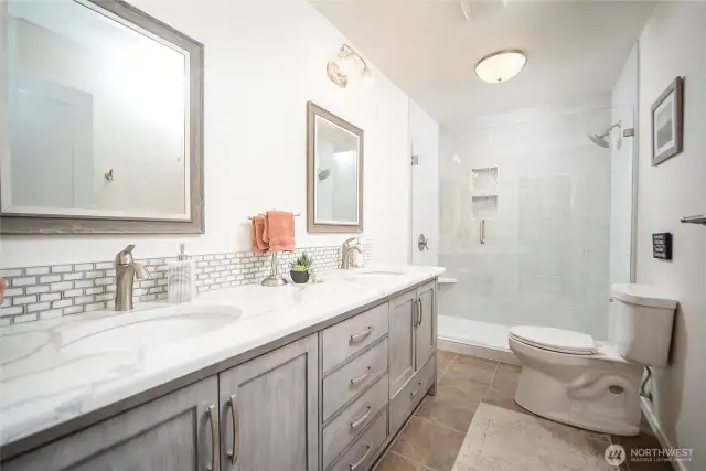 Main bathroom again with quartz counters and walk-in tile and glass shower.