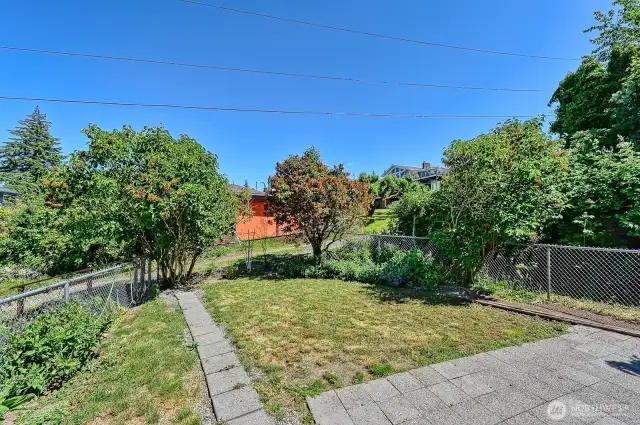 Fenced backyard with small patio.