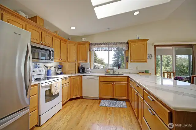 Chef's kitchen with stainless steel refrigerator and microwave, granite countertops, wood floors, ample cabinet space and more!