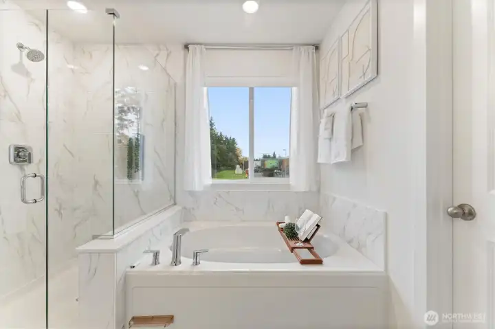 Luxurious primary bath featuring soaking tub, glass-enclosed shower, and abundant natural light.