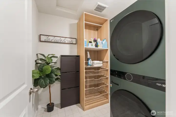 Convenient laundry area with full-size stacked washer and dryer and built-in shelving.