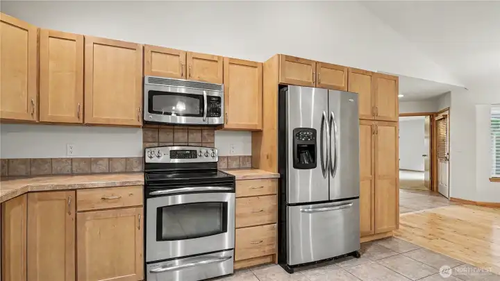 Kitchen features matching stainless steel appliances, natural toned cabinetry with plenty of counter space and storage.