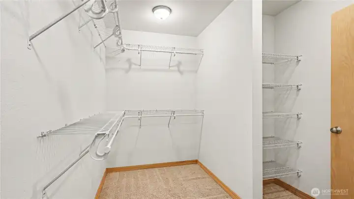 Spacious walk-in closet featuring built-in shelving for added organization.