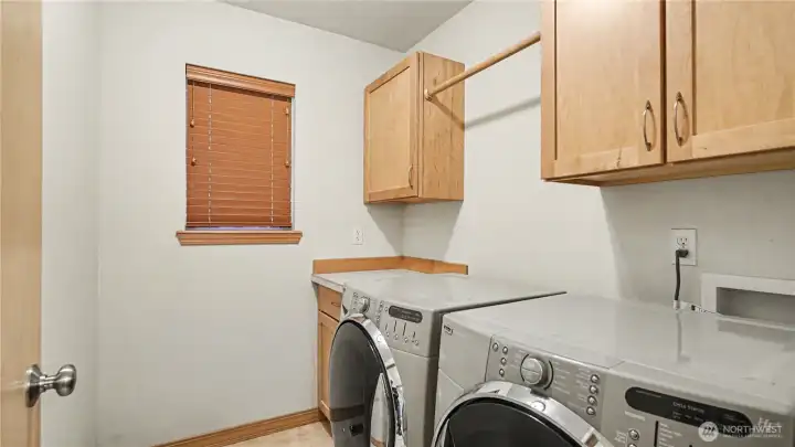Functional laundry room featuring extra storage and a convenient drying bar.