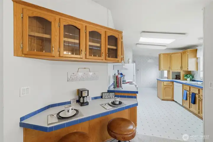 Breakfast bar area with custom seatings. Designer accents include colored tile edgings and custom cabinets with open glass doors for collectibles , dinner wear etc.