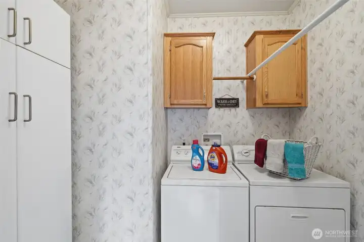 Utility room has storage cabinets above the washer and dryer and additional storage cabinets for all your cleaning and laundry needs.