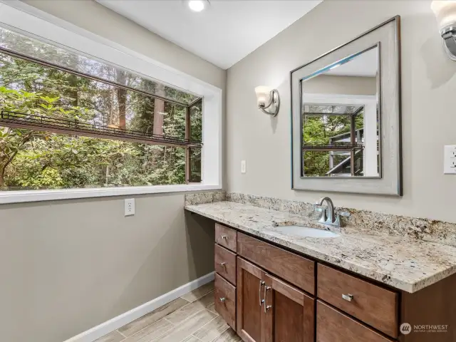 Spacious basement bathroom with large vanity and window looking out to back yard