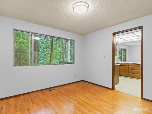 Dining room off kitchen opens up to living room with window overlooking back yard and private setting