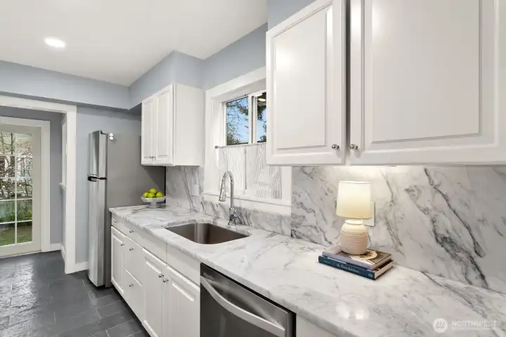 Galley kitchen off of the Formal Dining room enjoys beautiful Carrara Marble counters and backsplash with stone floors.