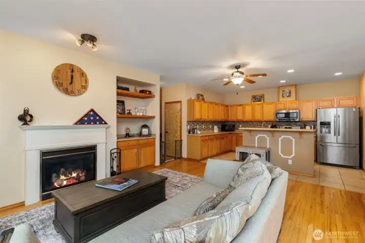 Bright open concept living, featuring rich hardwood floors, and gas fire place with classic white mantel.