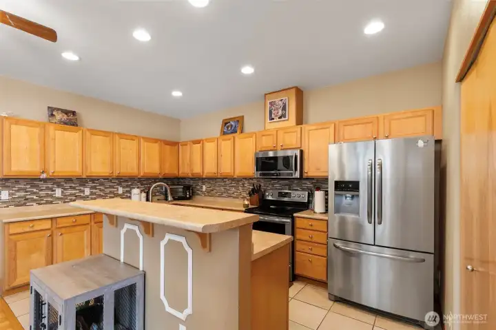 Chef-inspired Kitchen with abundant cabinetry, stainless fridge, oven, and microwave.