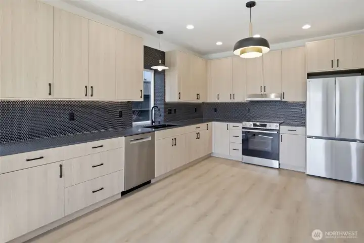 Contrasting light wood cabinetry with ebony fixtures and stainless steel appliances. Flexible space for a chef's dining table or workspace. Contrasting light wood cabinetry with ebony fixtures and stainless steel appliances. Flexible space for a chef's dining table or workspace.