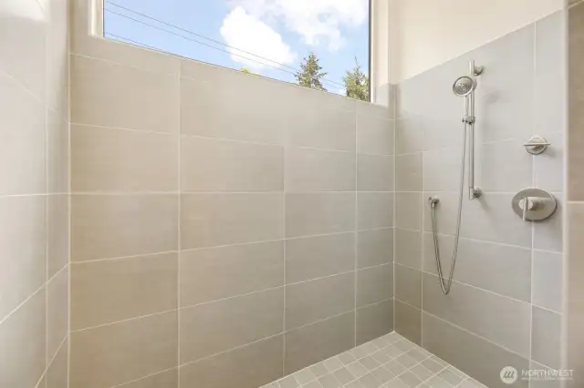 Fully tiled & oversized, room for 2, primary bath shower with custom  glass doors and an oversized high windows for natural light.