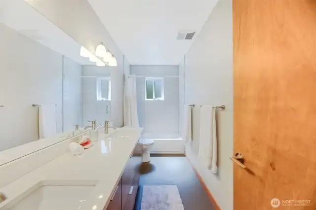 Full bath with double sinks, tiled shower and S facing window for natural light.