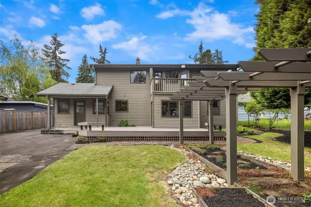 Spacious backyard with newer deck, perfola, shed/shop, and detached garage.