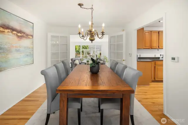 Dining room with hardwood floors looking through french doors into the sun room / office.