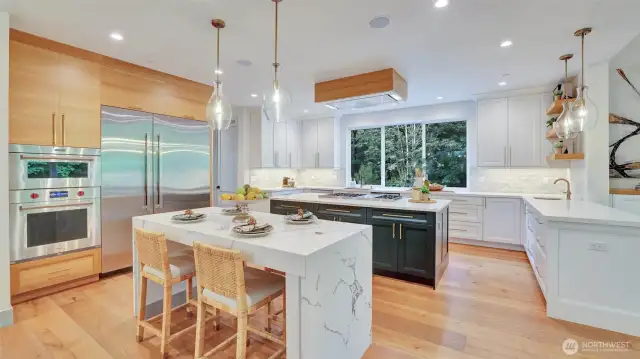 At the heart of the home, the chef’s kitchen is a showpiece of style and functionality, with fresh white cabinets, gleaming quartz countertops, white oak accents, floating shelves and champagne bronze hardware.