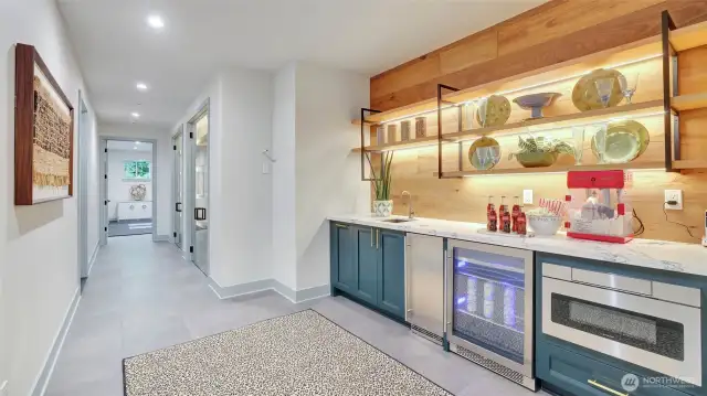 A stylish café bar with mini-fridge, icemaker, microwave and ambient lit floating shelves adds convenience.
