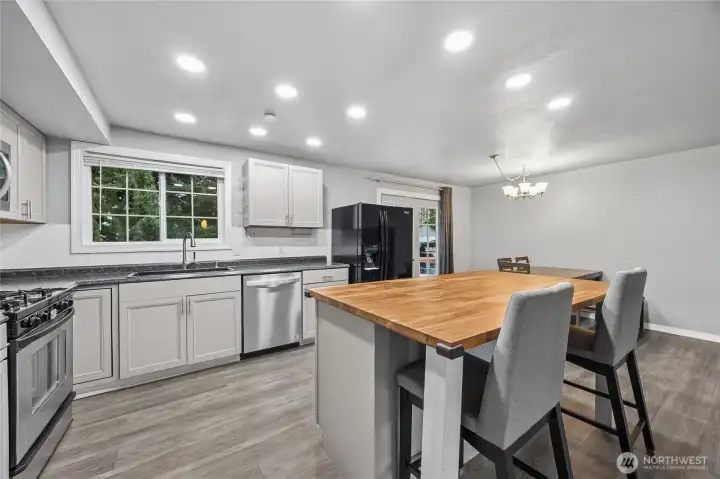 Angled kitchen view highlighting the center island with butcher block countertop for added prep space.