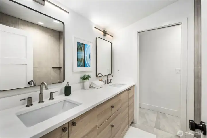 Primary bath includes double undermount vanities, white quartz countertops and cool lighting
