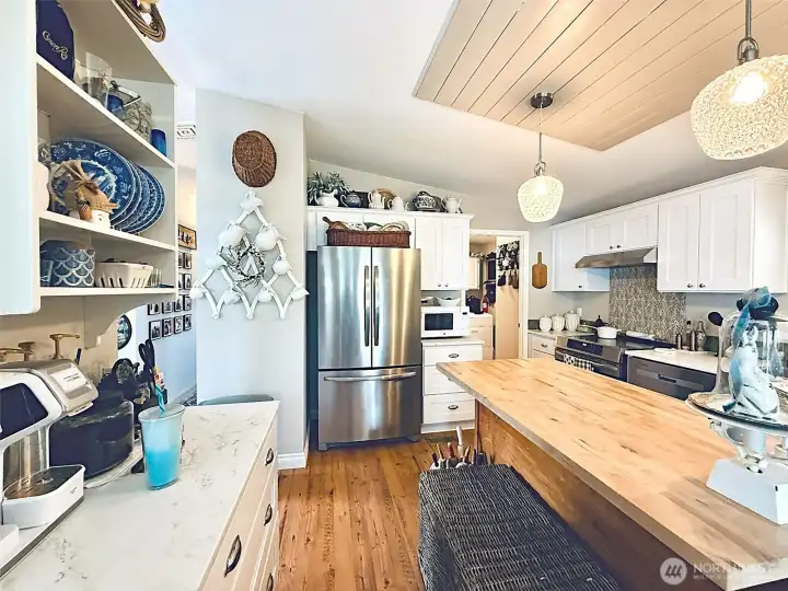 Dining room looking towards kitchen, island, additional storage with a coffee station, flows to laundry room that has a pantry and access to govered parking