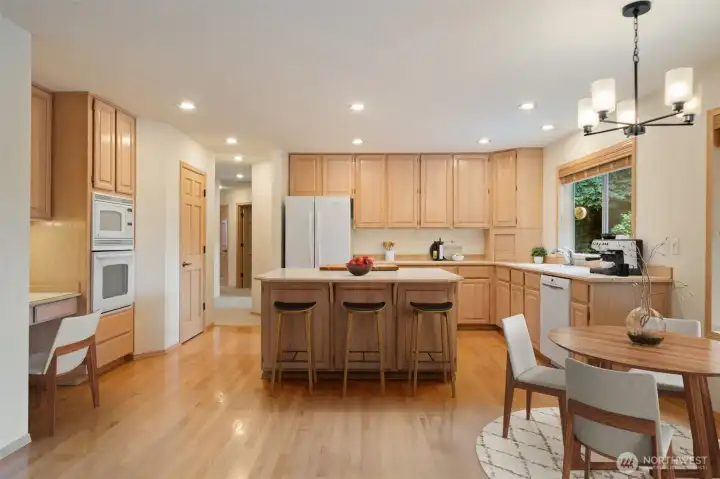 Open Air Kitchen with center island & bar stool area, eat in kitchen, wood floors & cabinets, open to family room with slider to large entertainment size deck & trails below. Virtually staged to show you size and potential!