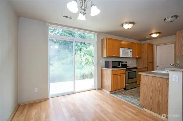 The dining area features sliding glass doors that open to a backyard patio overlooking a lush greenbelt.