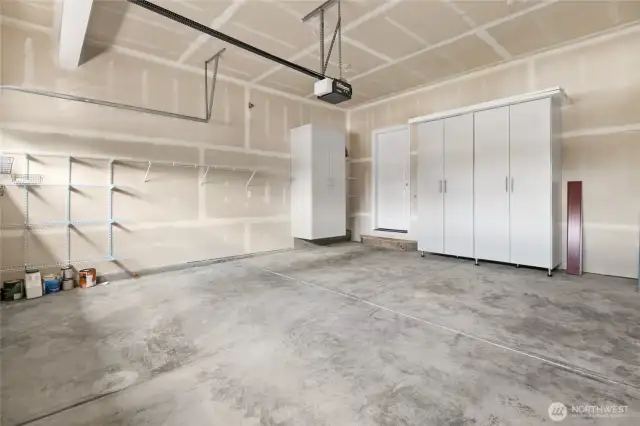 The garage offers shelving and cabinet storage.