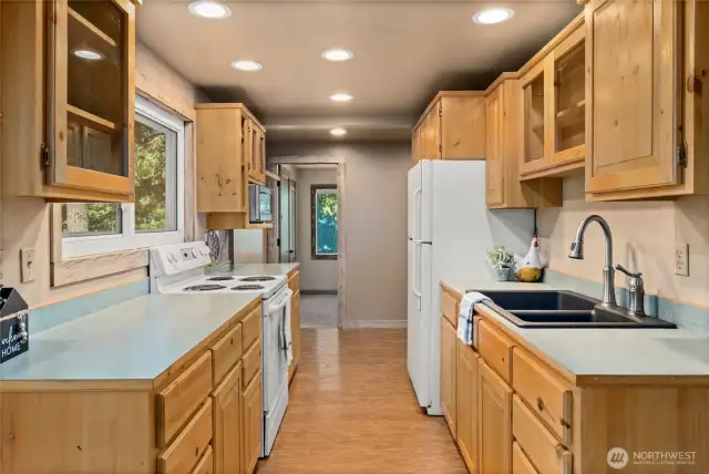 Kitchen with stove, full size refrigerator, microwave and large sink.