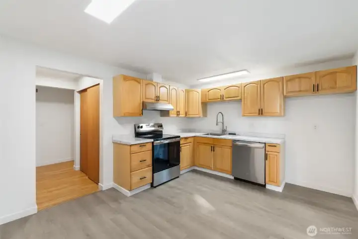 Updated kitchen with maple cabinets, new stainless steel appliances, and waterproof vinyl flooring.