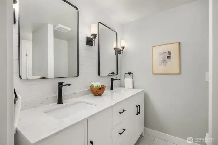 The recently updated bathroom features shiplap wall detail, dual sink vanity, new flooring and new shower with glass door.