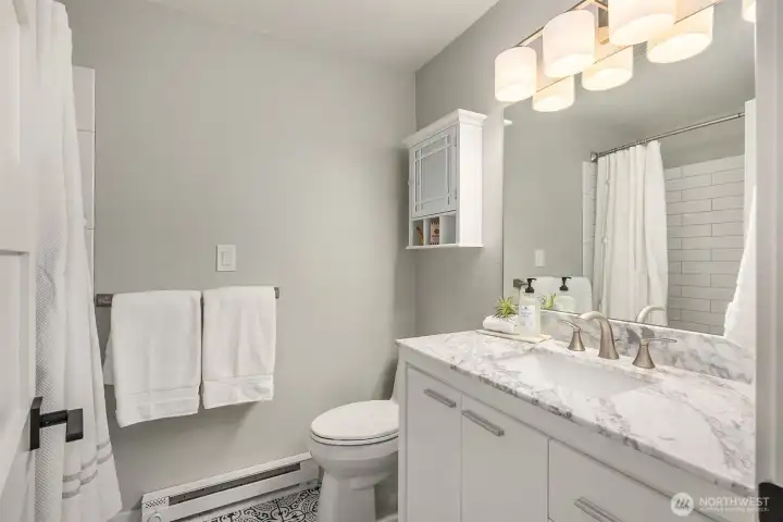 Second full bathroom in the lower level features a large vanity with a spacious marble countertop and lots of storage.
