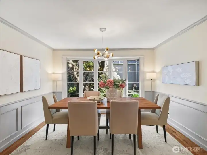 The formal dining room is anchored by a designer light fixture and framed by a stunning tree trunk view—almost like living artwork that creates an unforgettable focal point and conversation piece.