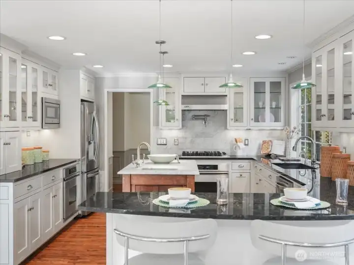 The kitchen shines with Viking appliances, a marble island, and a sunny eat-in space—elevated even further with in-cabinet lighting that adds a warm, polished glow.