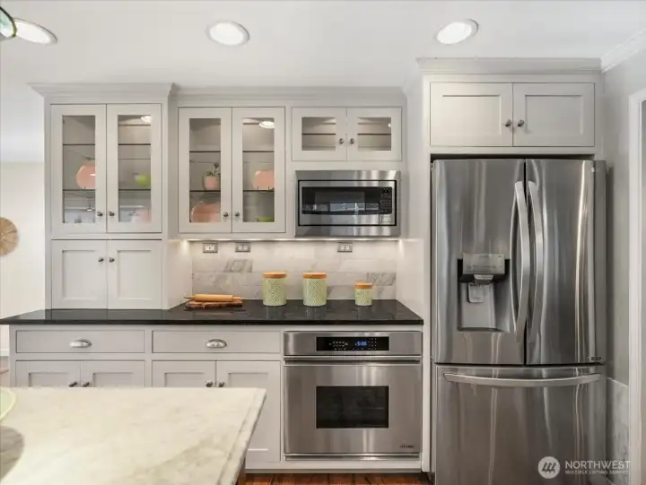 Glass-front cabinetry with integrated lighting and elegant under-cabinet lighting adds warmth, depth, and a refined touch throughout the kitchen.