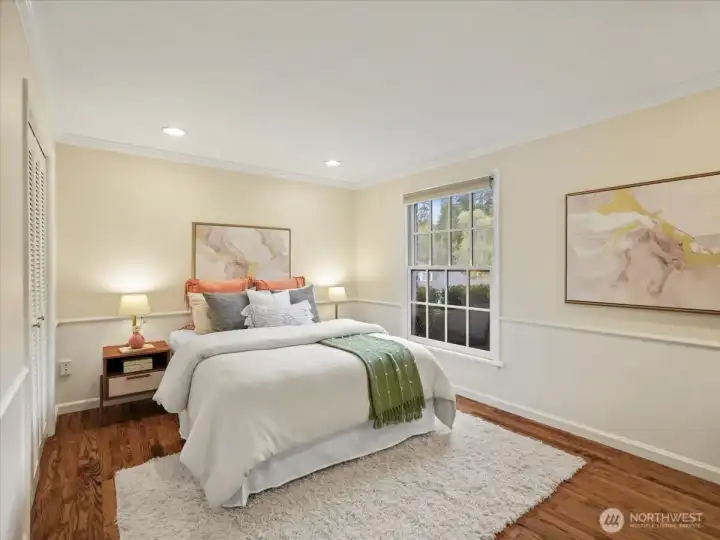 Another view of the main floor bedroom, highlighting east-facing windows and generous closet space.
