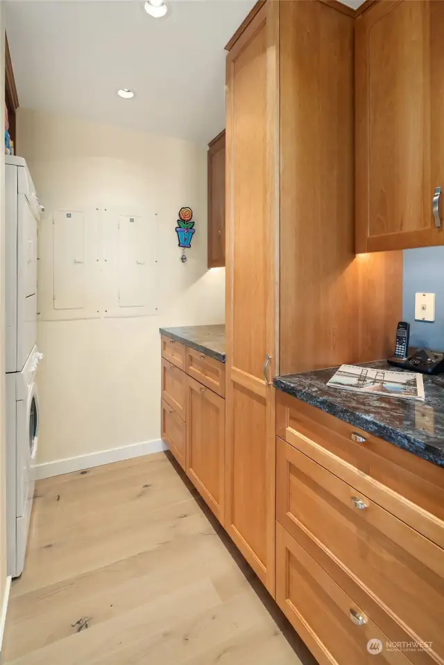 Laundry room with stacking washer and dryer, granite countertops and apple built-in storage.