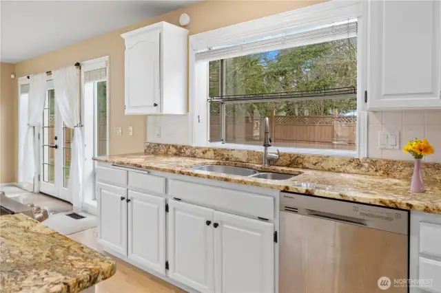 Granite counters, freshly painted cabinets, dual sinks, and a view to the private courtyard are some of the wonderful features in the spacious kitchen.