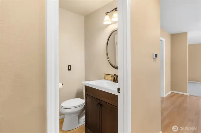 The powder room has been refreshed with newly textured and painted walls, new sink, vanity, toilet & lighting.