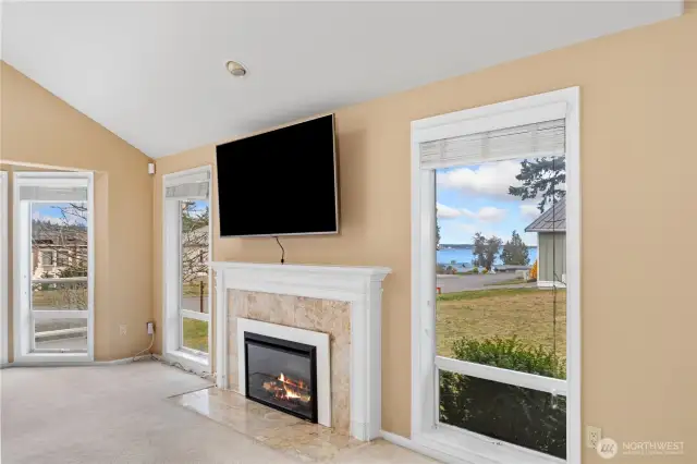 The big windows frame the nice water views from the living room, which is warmed by the electric fireplace.