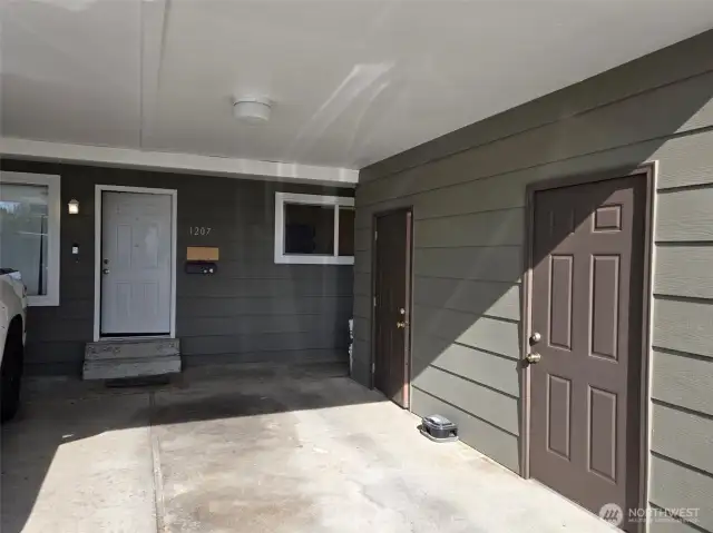 Brown doors show designated storage for each unit under carport.