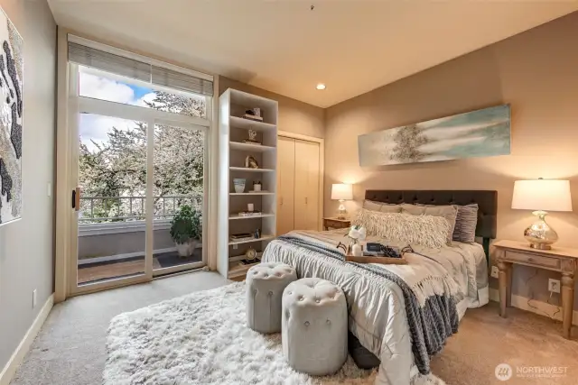Guest bedroom with view of flowering cherry tree and slider to balcony.