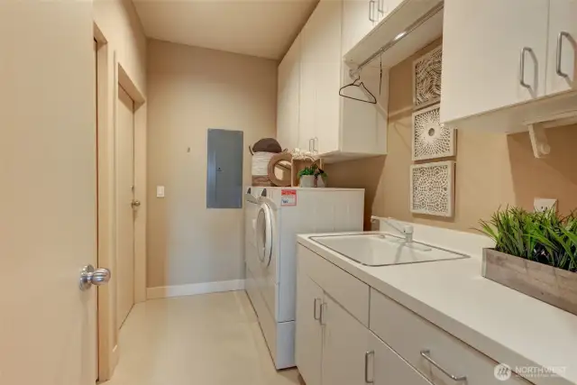 Laundry room with ample cabinets, laundry sink and walk-in closet for extra storage. Door leads to back stairwell.