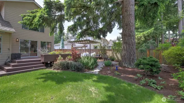 Behold this exquisite wooden deck surrounded by distinctive landscaping, mature trees, and artfully arranged decorative stones that guide you toward secluded seating and private retreats