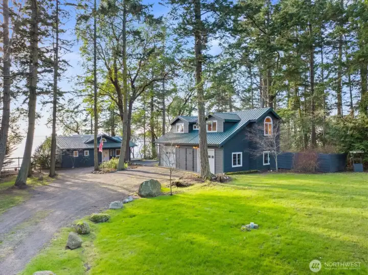 Private drive leads to spacious garage and studio, surrounded by towering evergreens and natural island beauty.