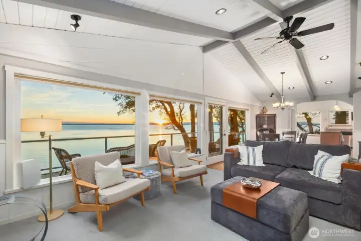 Inviting living area with expansive windows and deck access, blending indoor comfort with outdoor waterfront living on San Juan Island.