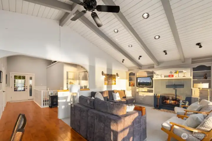 Sun-drenched living room with fireplace, built-ins, and wall of windows framing panoramic marine views—perfect for cozy evenings overlooking the water.