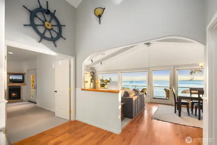Airy hallway with vaulted ceilings and warm wood flooring leading toward the main living spaces, showcasing the home’s thoughtful layout and coastal design.