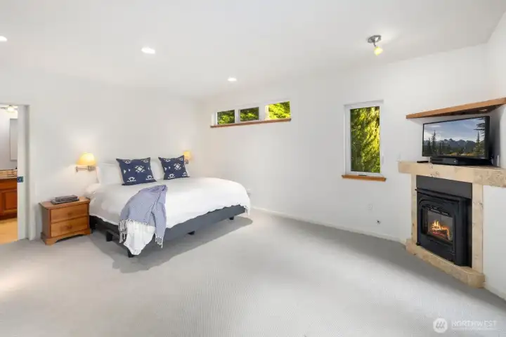 Expansive primary retreat with fireplace, serene ambiance, and refined simplicity—designed for comfort and privacy in this waterfront sanctuary.